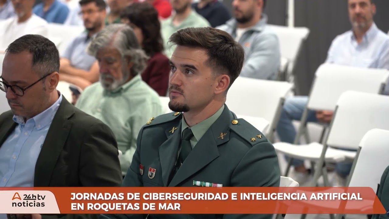 Fotograma del reportaje de Almería 24h TV sobre las jornadas de ciberseguridad e inteligencia artificial en Roquetas de Mar, con el público y un oficial de la Guardia Civil en primer término